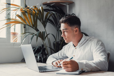 Side view of man using laptop at home