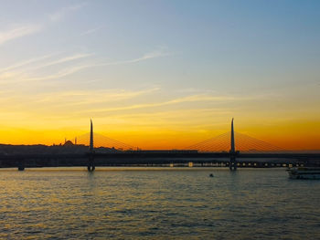 View of suspension bridge over river at sunset