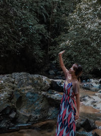 Woman standing on rock against trees