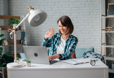 Young woman using mobile phone while sitting on table