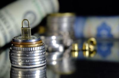 Close-up of padlock on stacked coins