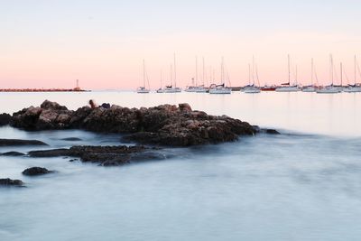 Sailboats on sea against clear sky during sunset