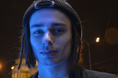 Close-up portrait of young man in city at night