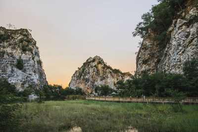 Scenic view of rocks by trees against sky