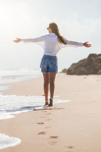 Full length of young woman standing at beach