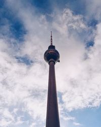 Low angle view of communications tower against cloudy sky