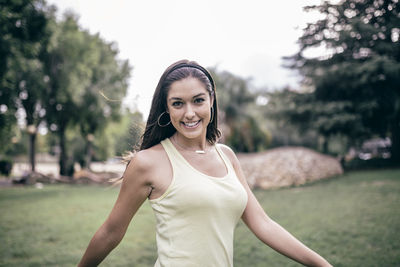 Portrait of smiling young woman standing against trees