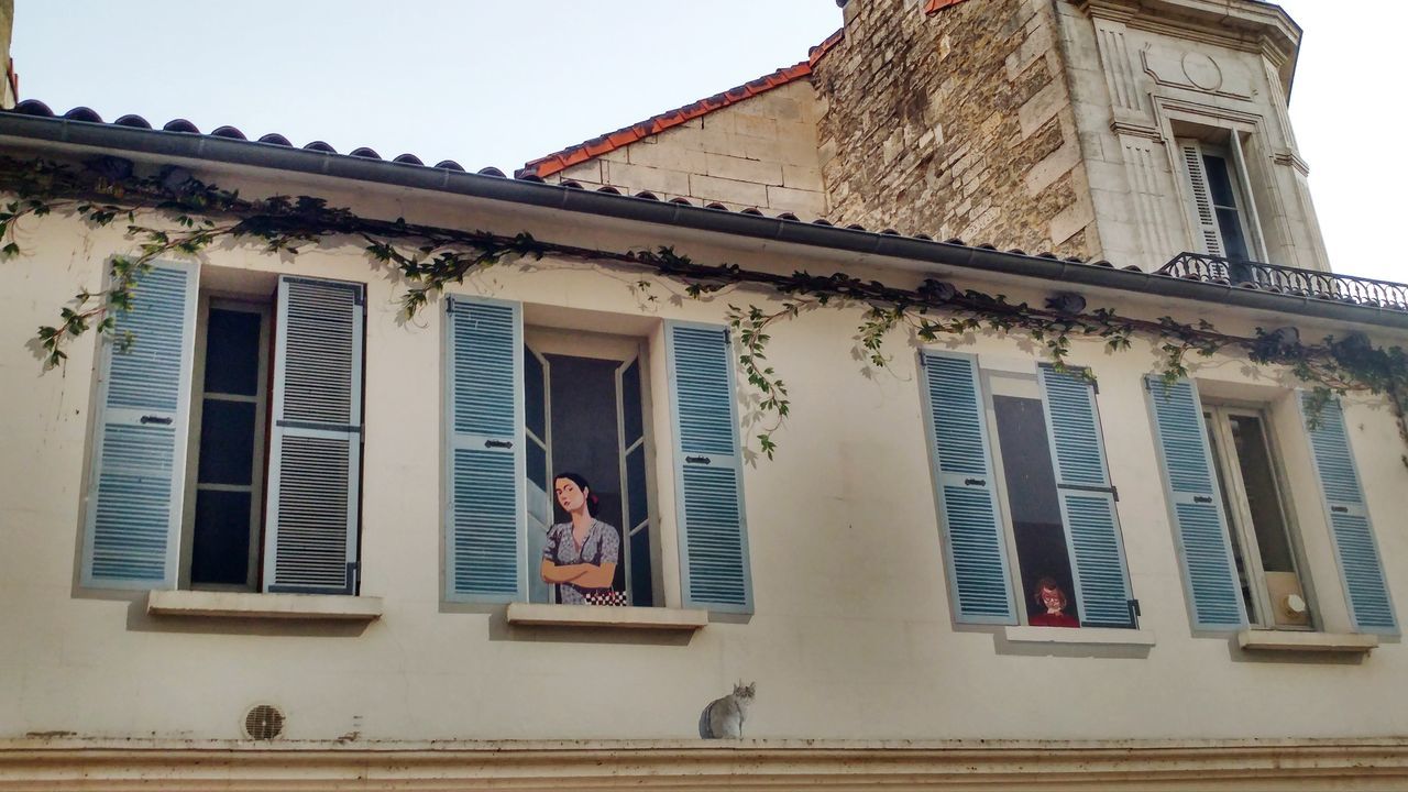 LOW ANGLE VIEW OF MAN SITTING OUTSIDE HOUSE