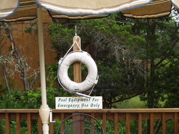 Information sign hanging on rope against trees