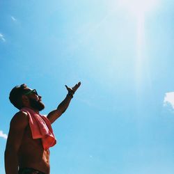 Low angle view of shirtless man against blue sky
