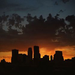 Silhouette of cityscape against sky at sunset