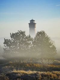 Tree by lighthouse against sky