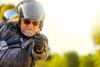 A motorcyclist with a helmet and sunglasses gives a friendly greeting