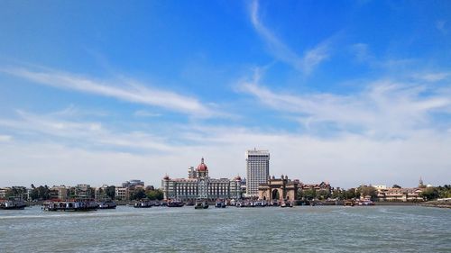 Buildings by sea against blue sky