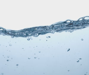 Close-up of water drops on glass against white background