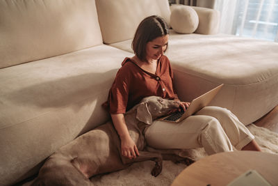 Young woman sitting on sofa at home