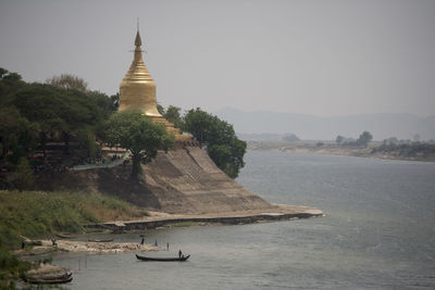 Pagoda at riverbank against sky