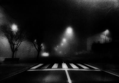 Empty road along trees at night