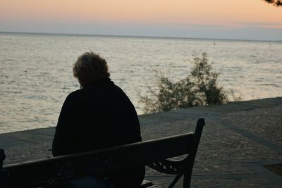 Couple sitting on calm sea at sunset
