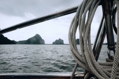 Close-up of sailboat sailing in sea against sky