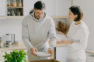 Couple arranging plates in kitchen