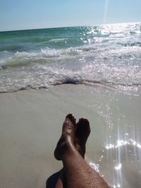 Low section of man on beach against sky