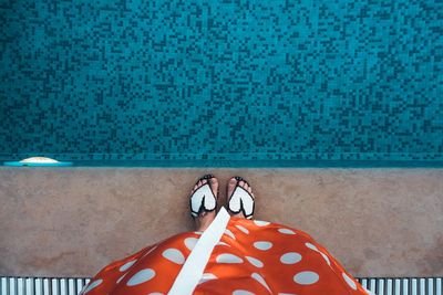 Low section of person standing by swimming pool