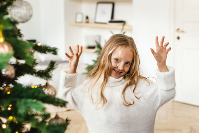 Portrait of happy girl with arms raised at home