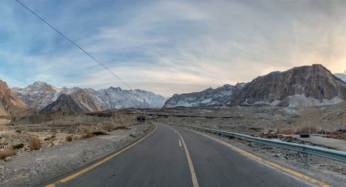 Road by mountains against sky during winter