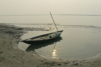 Boat moored on beach against sky