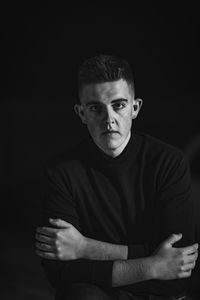 Portrait of young man against black background