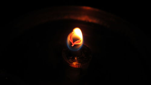 Close-up of illuminated candle in darkroom