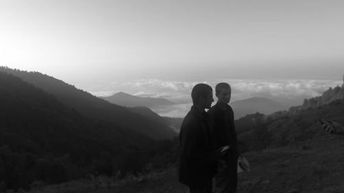 Friends standing on mountain against sky