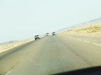 Vehicles on road against clear sky