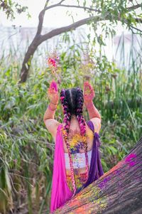 Rear view of woman with pink umbrella standing against plants