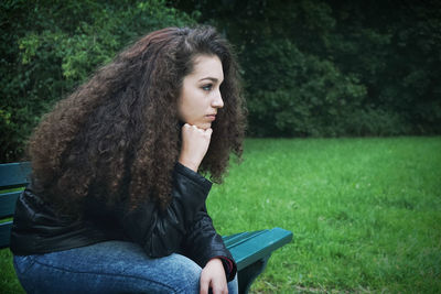 Thoughtful young woman sitting on park bench