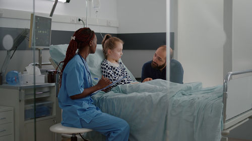 Nurse talking with girl with father at hospital
