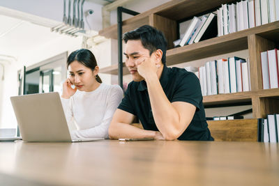 Business persons brainstorming while looking at laptop in office