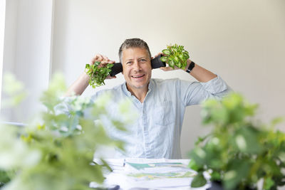 Man covering ears with potted plants against wall