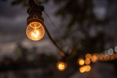 Low angle view of illuminated light bulb against sky at night