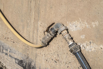 Old water valve connected to a hose, in the factory installed outside by the wall.