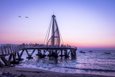 Pier over sea against clear sky during sunset