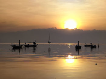 Silhouette boats in sea against sky during sunset