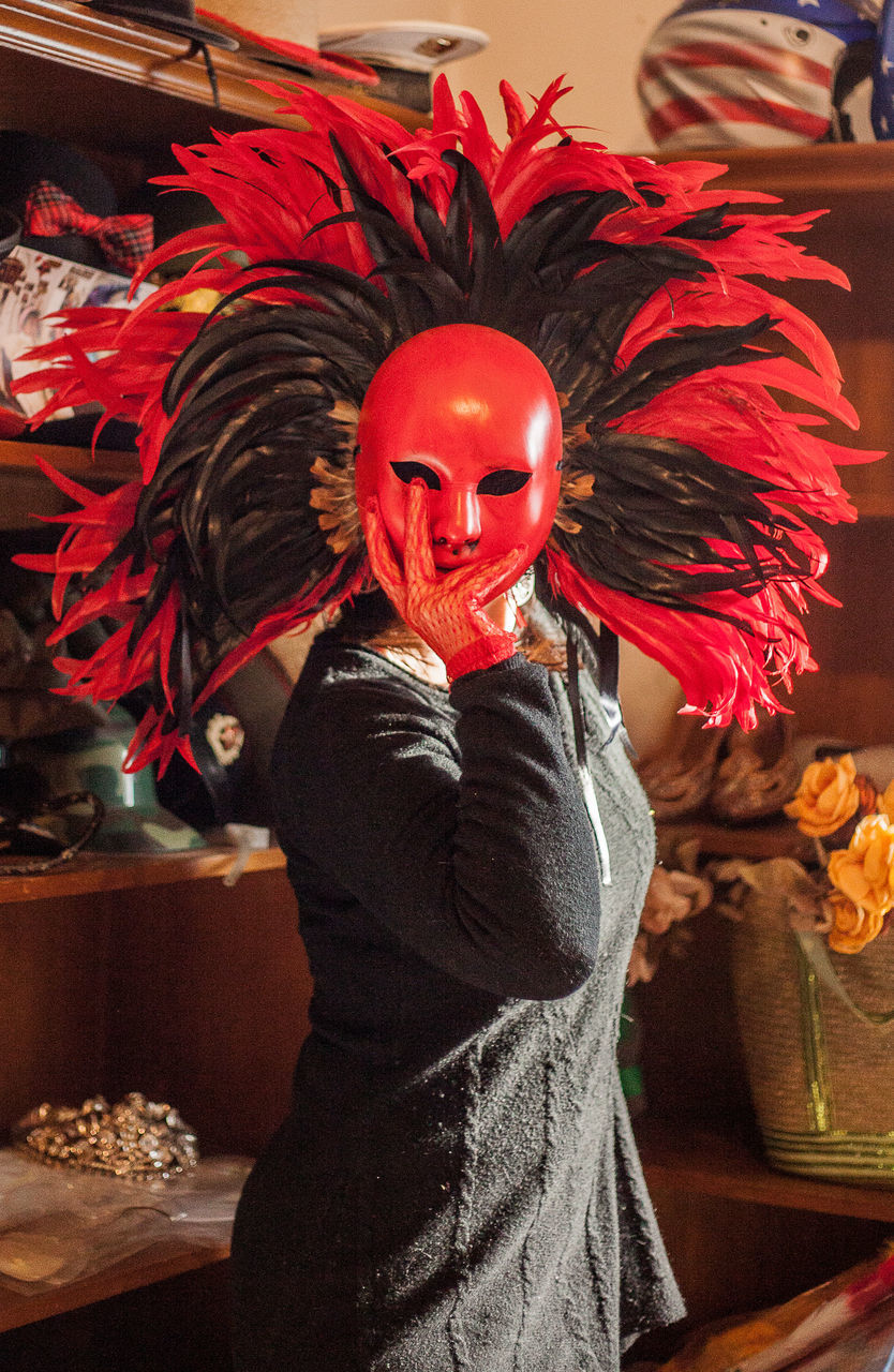 MIDSECTION OF PERSON WEARING MASK STANDING BY RED UMBRELLA