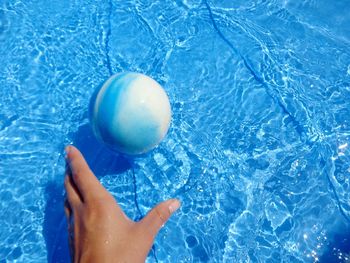 Low section of person with ball in swimming pool