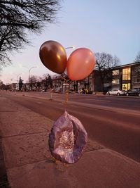 Balloons on street against sky in city