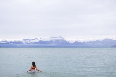 Rear view of man in sea against sky