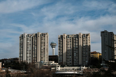 Skyscrapers in city against cloudy sky