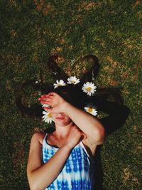 High angle view of woman with flowers on hair lying at field