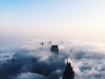 Clouds touching skyscraper in city against sky